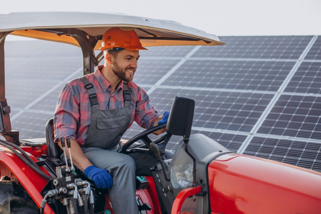 Agriculteur assis dans son tracteur qui passe dans un champs avec des panneaux photovoltaïques